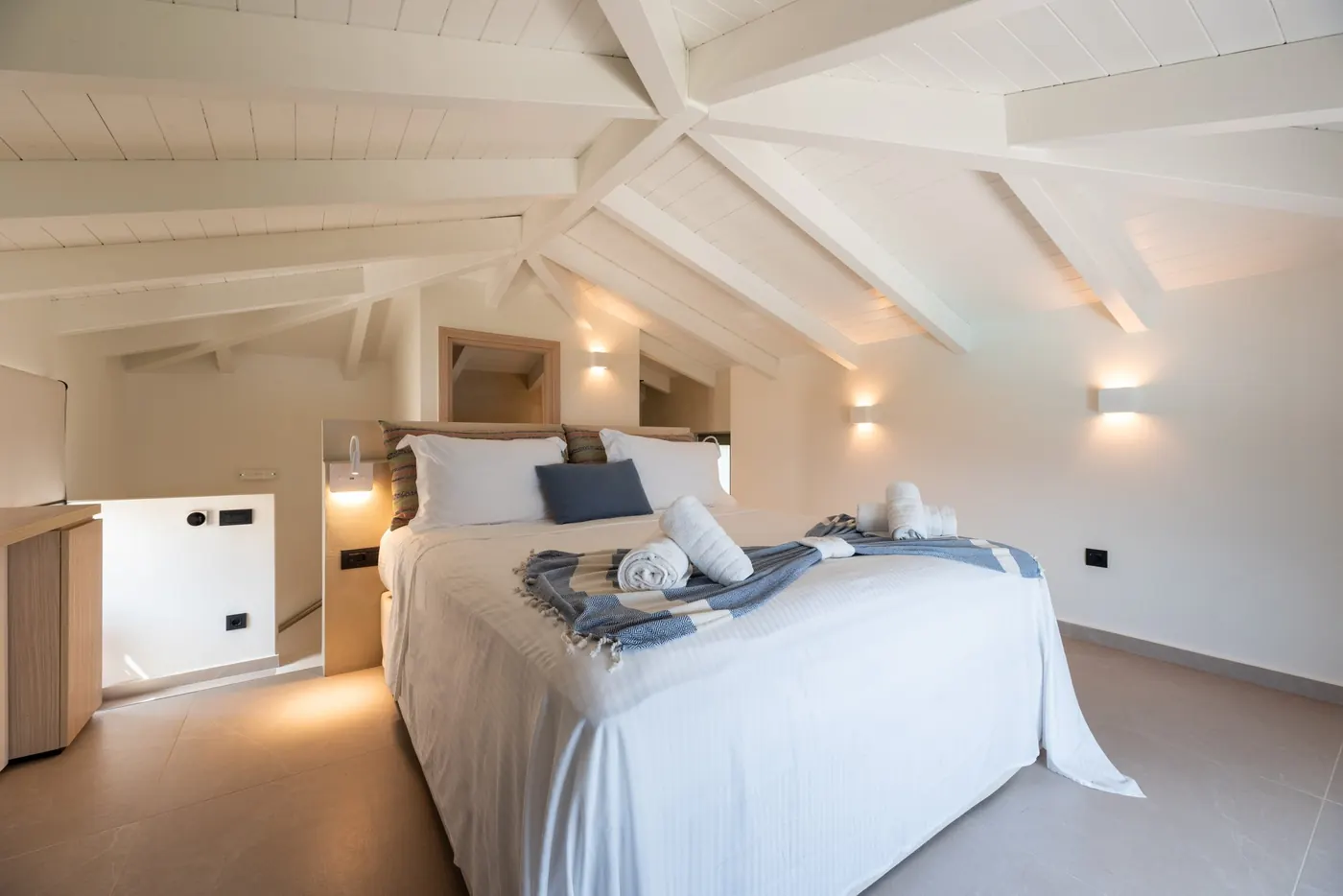 Upper-level bedroom at Alas beneath white beams