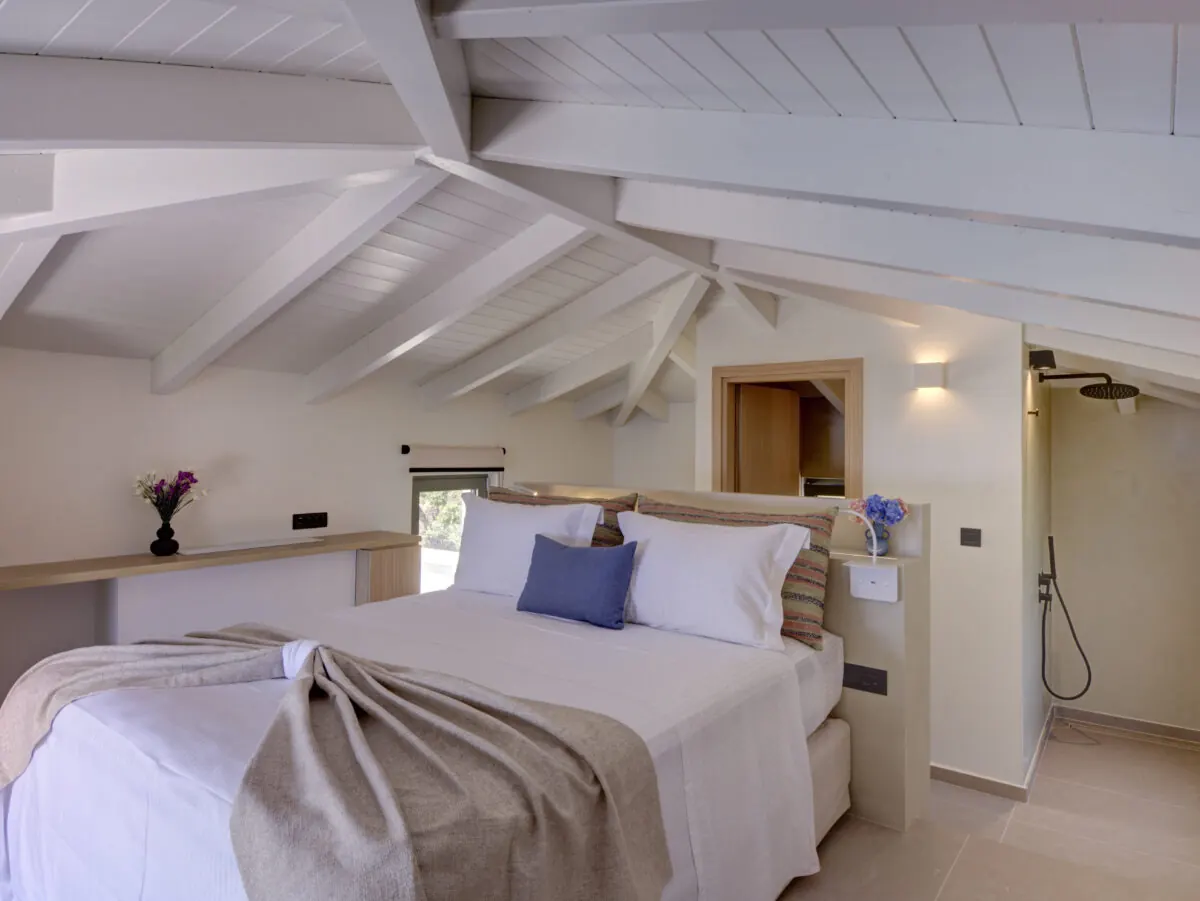 Upper-level bedroom beneath white beams at Alios
