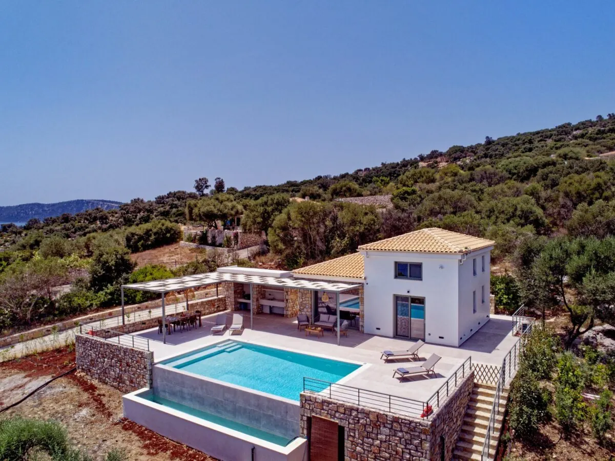 Aerial view of an Apílion villa, its infinity pool and the olive terraces above Limonari bay