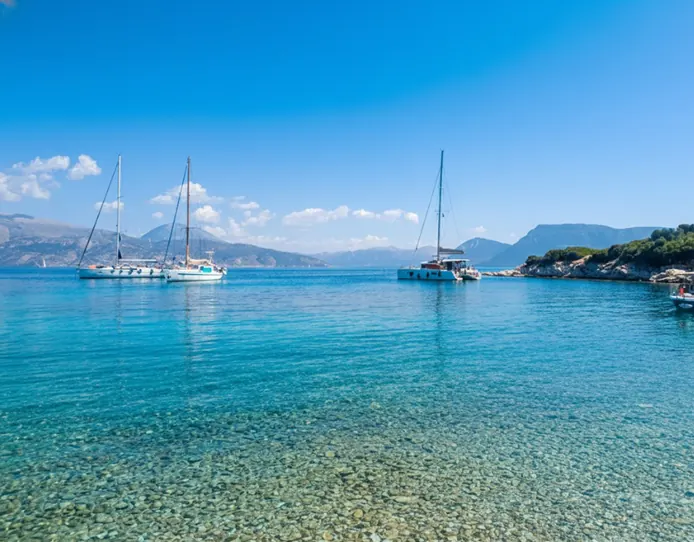 Sailboats anchored in turquoise water between the islands near Meganisi